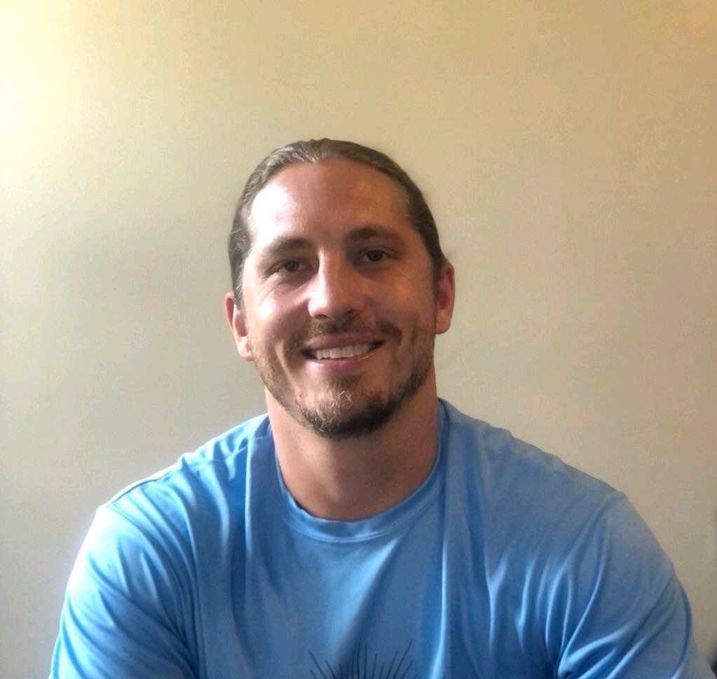 A man in blue shirt smiling for the camera.