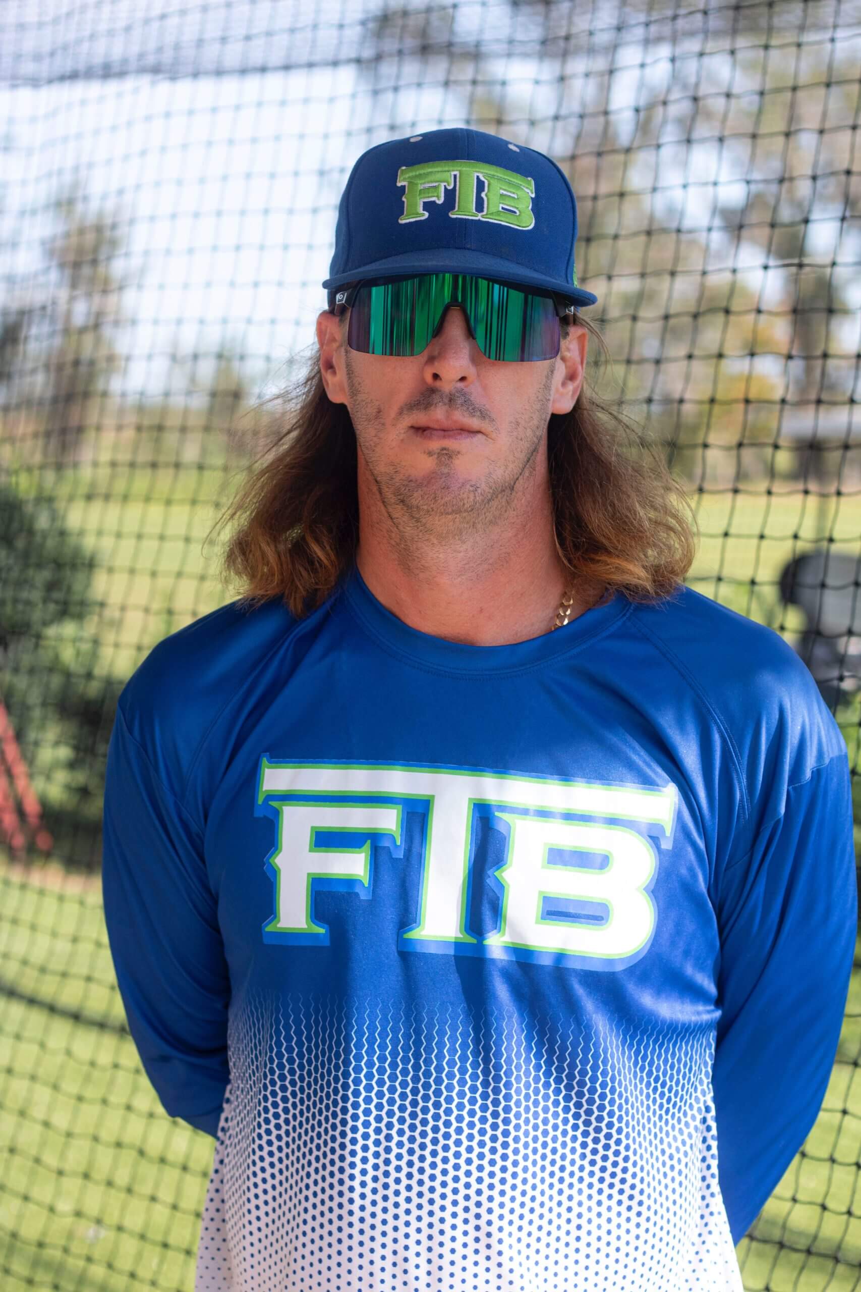 A baseball player wearing sunglasses and a blue shirt.